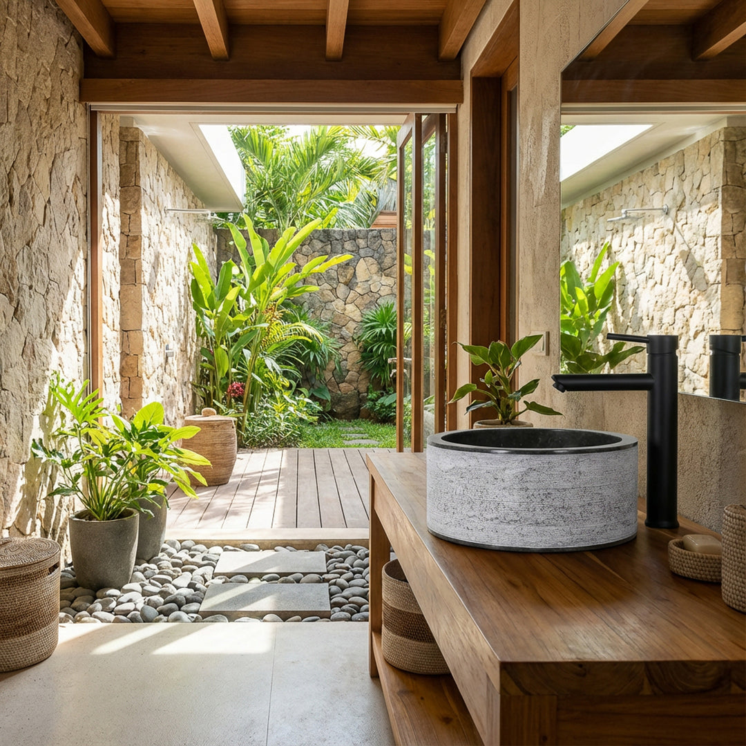 Round countertop washbasin in a light marble look on a wooden console, placed in the open bathroom with a garden view.