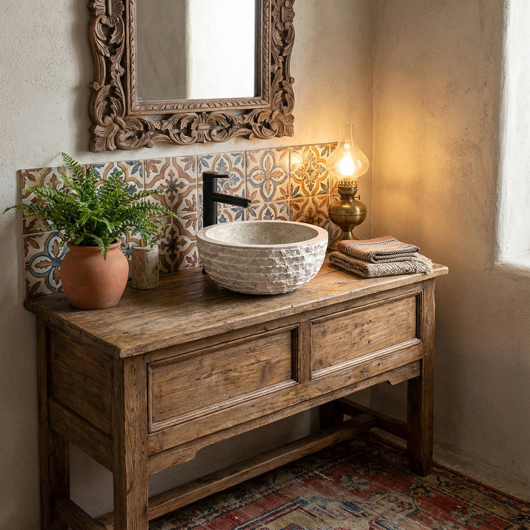 Round marble-look countertop washbasin made of stone on rustic wooden vanity unit in warm vintage bathroom with tiles