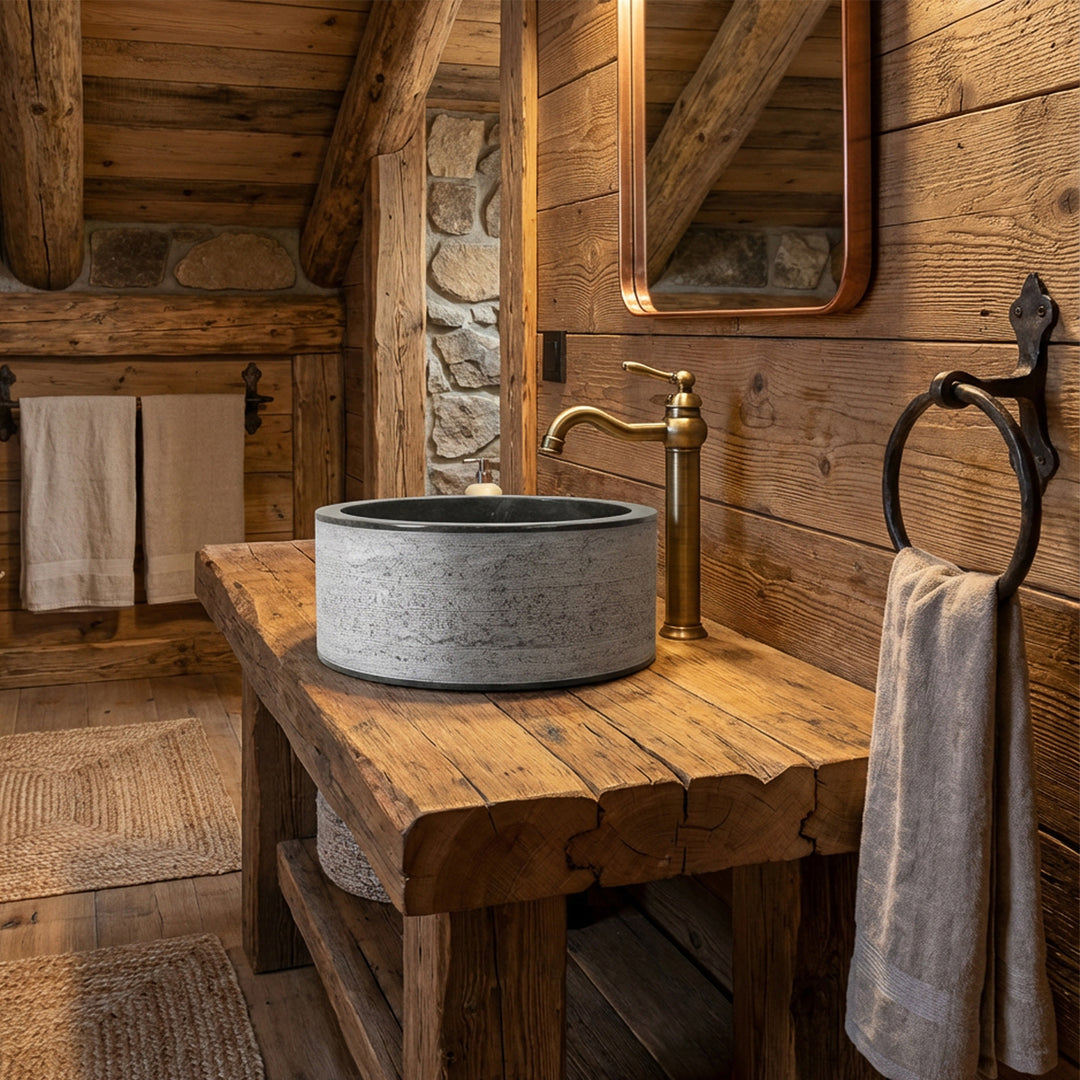 Round countertop washbasin made of stone on a solid wooden table, combined with brass fittings in a rustic chalet bathroom.