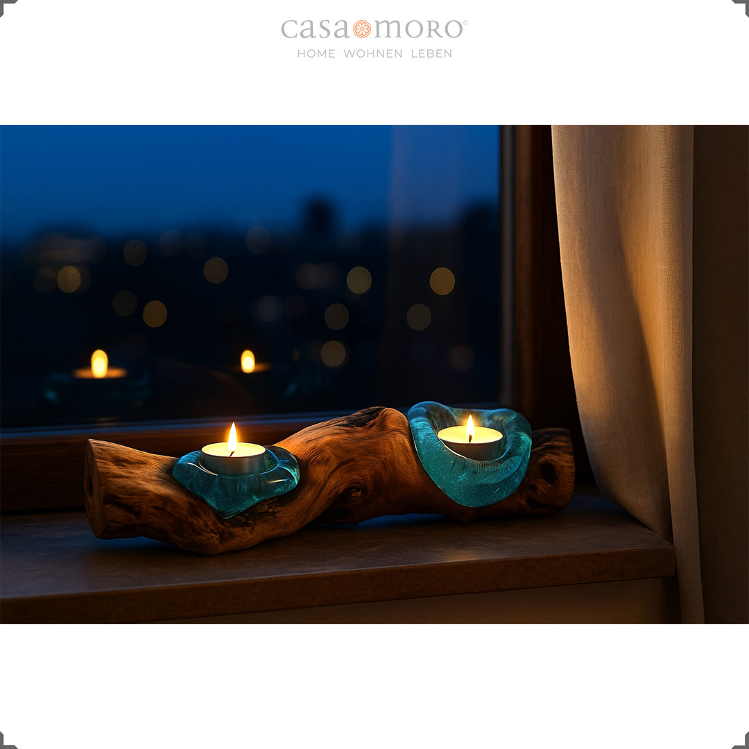 Länglicher Teelichthalter aus Glas und Wurzelholz auf einer Fensterbank, sein warmes Licht leuchtet sanft in die Abendstimmung hinaus.