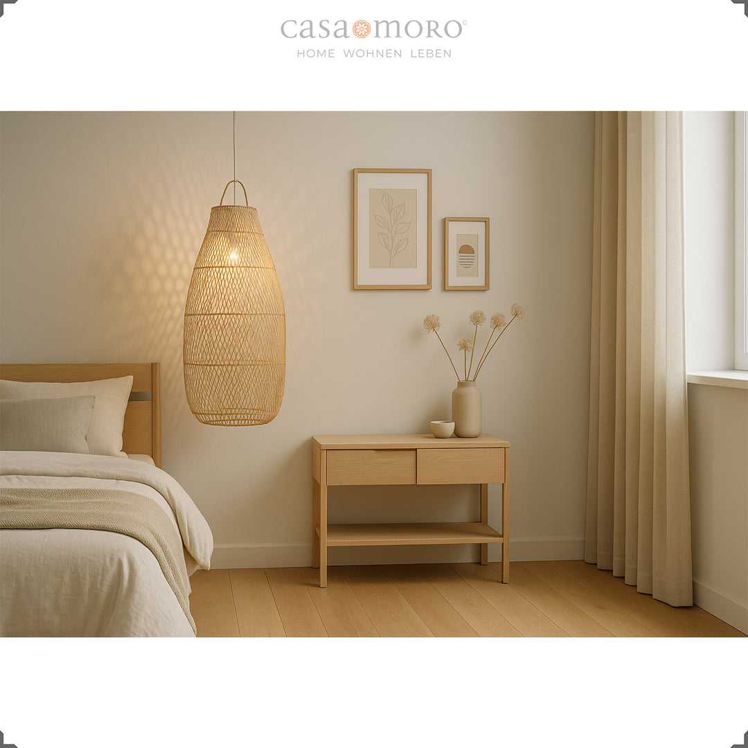 Hohe Rattanlampe im Schlafzimmer neben Bett, sanftes Licht und helle natürliche Einrichtung