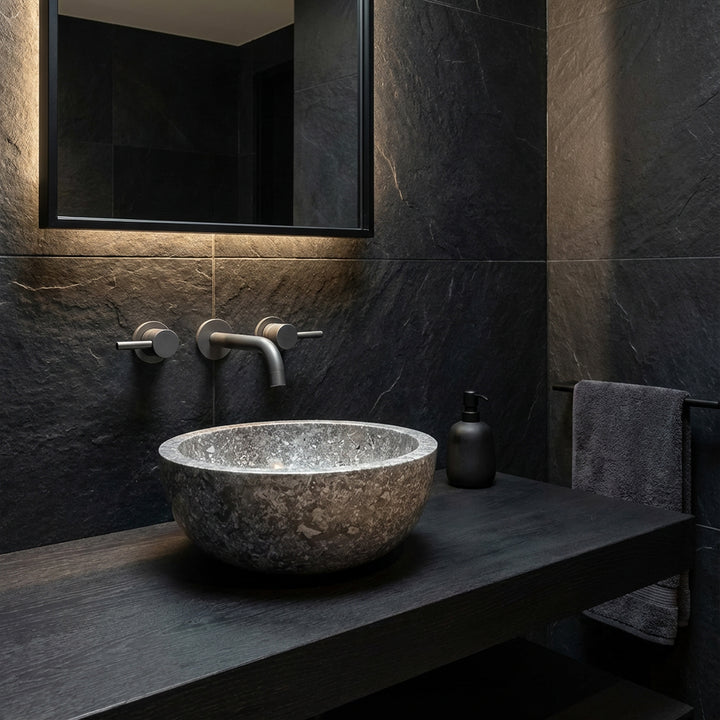 Round Washbasin made of dark natural stone as an attachment on a black console in a modern, minimalist bathroom ambience