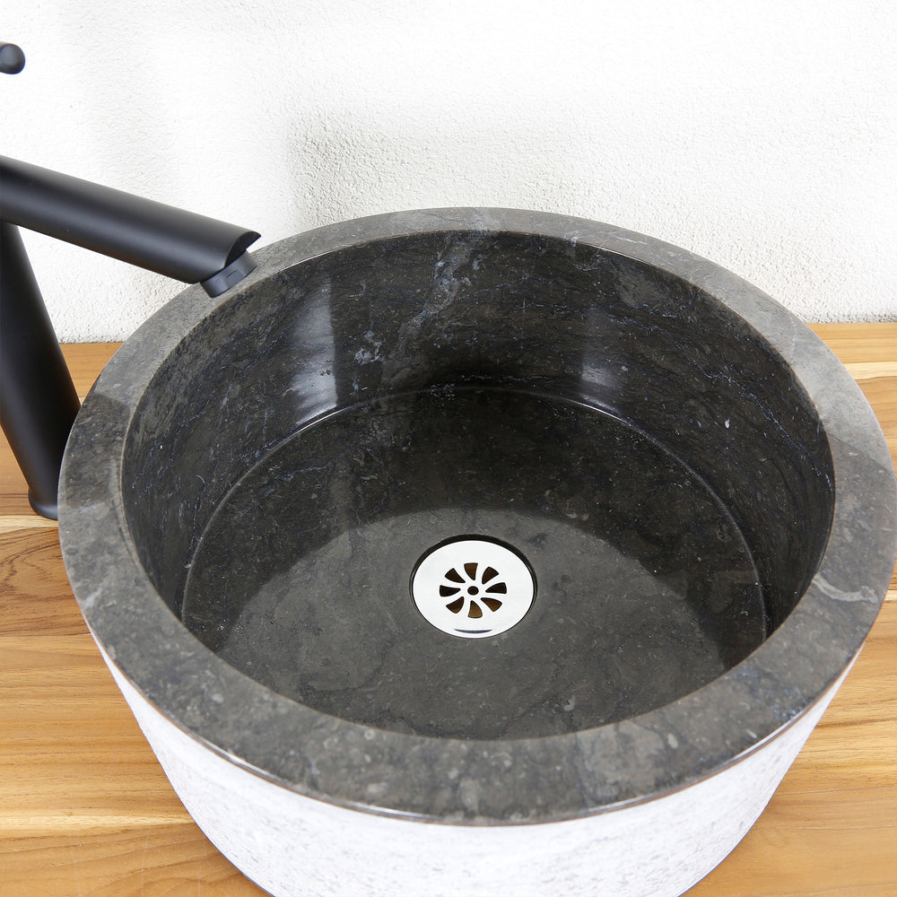 Detailed view of a round stone washbasin with a dark inner surface, precisely crafted and a clear design language.