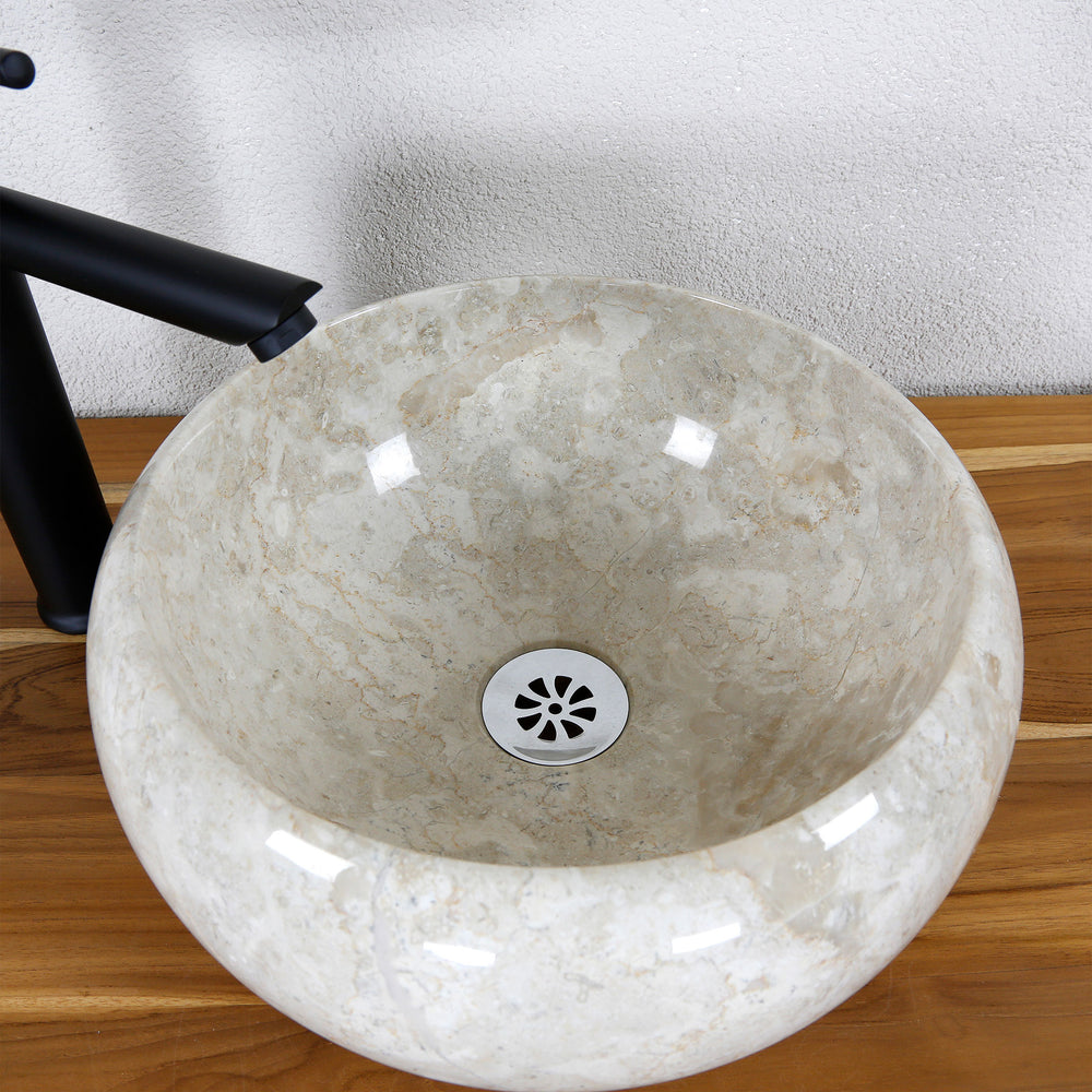 Detailed view of a round countertop washbasin made of light natural stone with a polished inner surface and a central drain