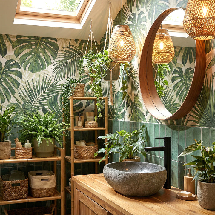 River stone countertop basin in green spa bathroom on wooden vanity unit, combined with black fittings and plant ambience