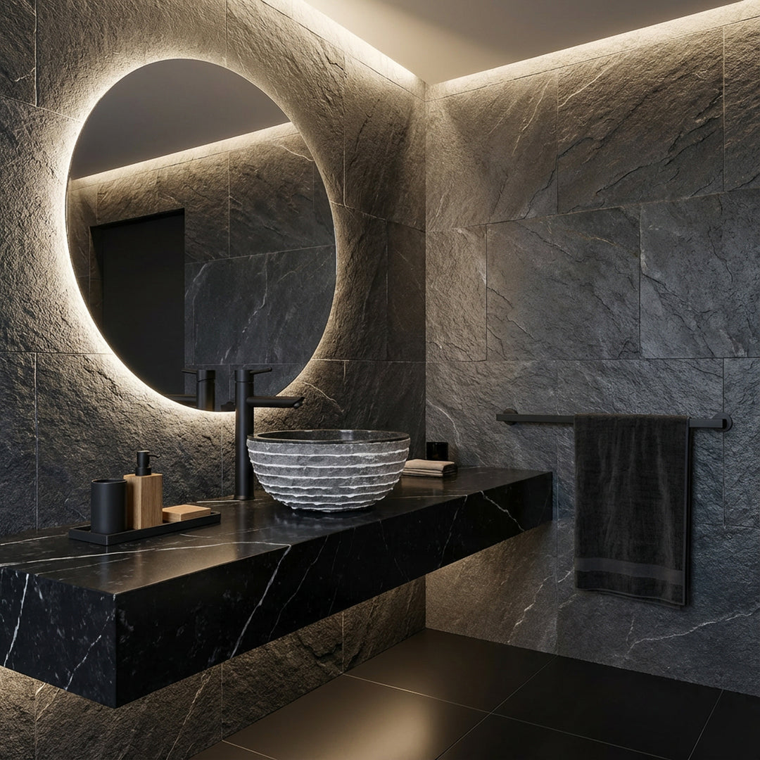 Round natural stone sink on dark vanity in modern spa bathroom with mirror, black faucet and indirect light