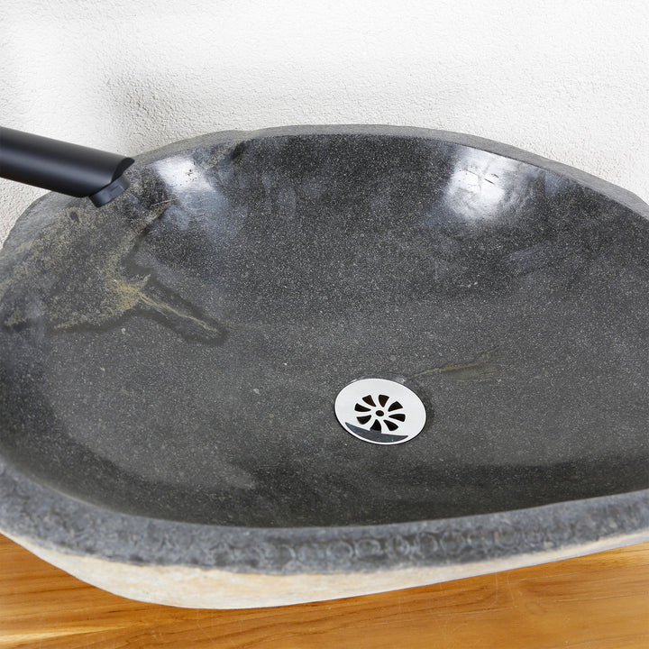 Detailed view of a stone basin with a finely polished inner surface, natural grain and a central drain