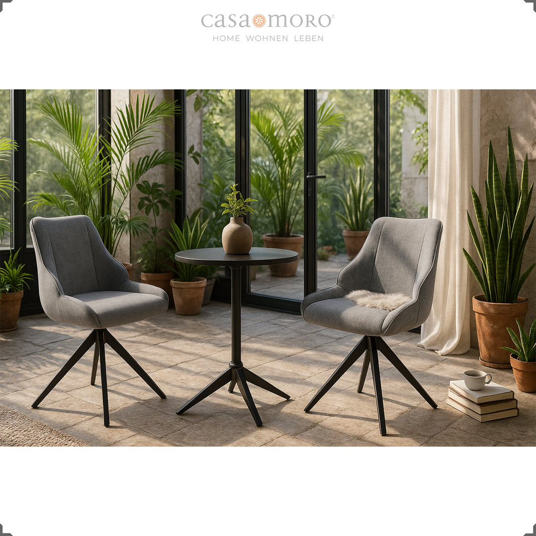 Zwei 360° drehbare Esszimmerstühle in Grau mit schwarzem Metallgestell, arrangiert im Wintergarten mit Pflanzen und natürlichem Licht