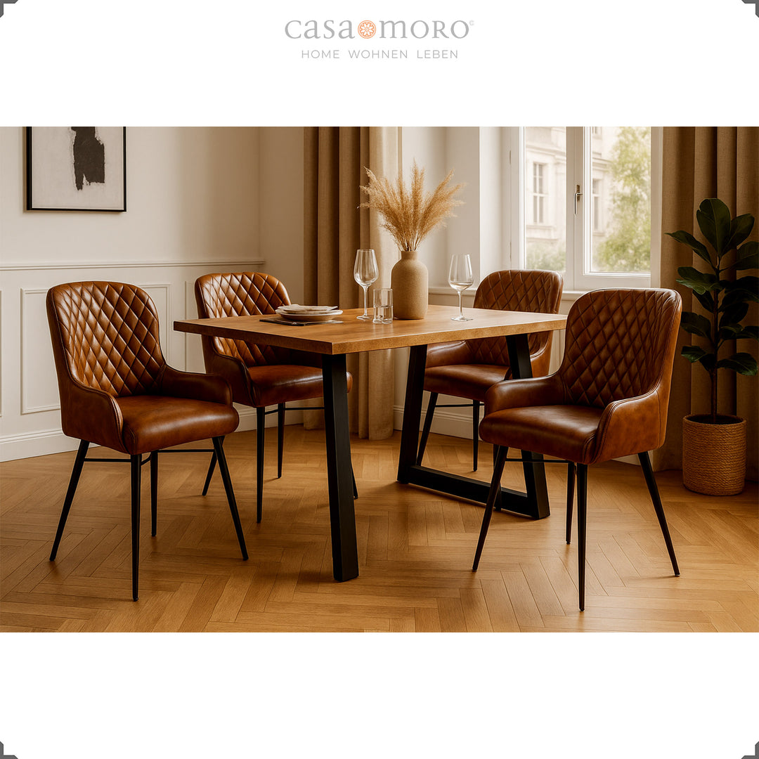 Vier antikbraune Lederstühle mit Rautensteppung an einem Holztisch in elegantem Esszimmer mit Parkettboden, heller Wandverkleidung und natürlicher Dekoration.