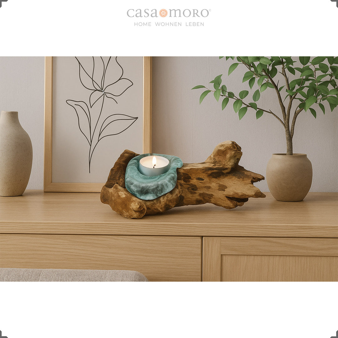 Teelichthalter aus Glas und Wurzelholz auf einem Sideboard, sein warmes Licht ergänzt die natürliche, schlichte Wohnraumdekoration.